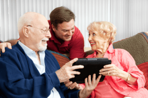 Image of senior couple being helped by a tech coach, from Shutterstock