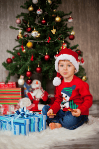 child with presents under Christmas tree, image from Shutterstock