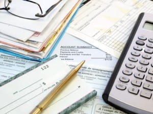 Pile of statements, checkbook and calculator, image from Shutterstock