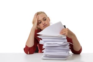woman-looking-at-stack-of-paper-image-from-shutterstock